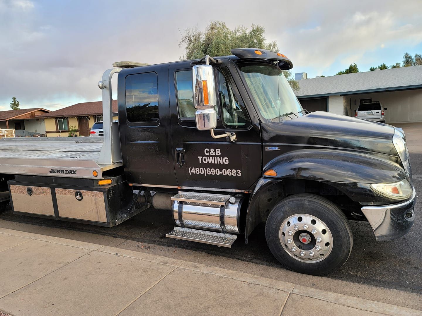 A black tow truck is parked on the side of the road.