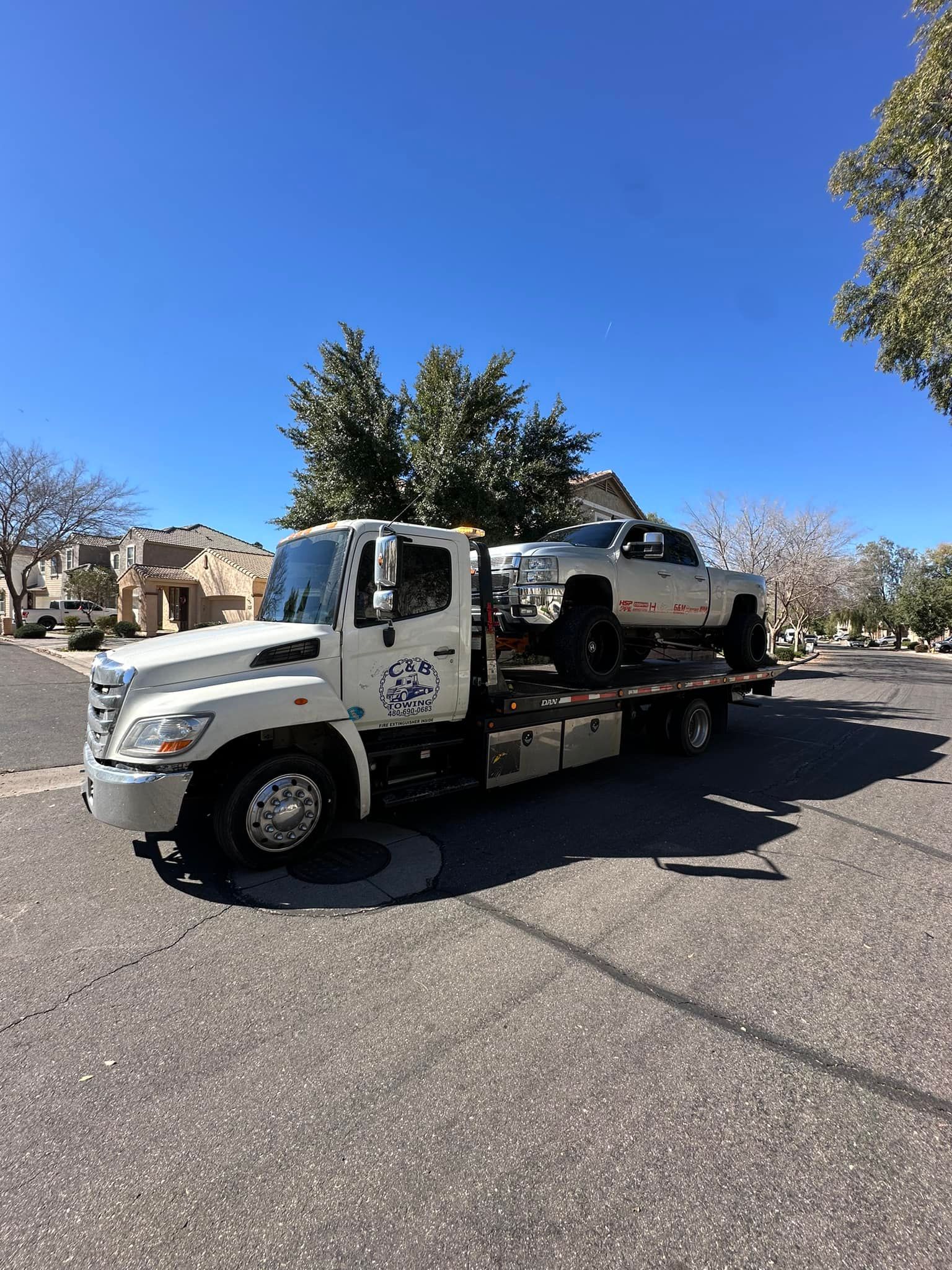 A tow truck is carrying a truck on the back of it.