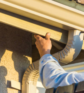 Person installing a light-colored gutter on a building's exterior.