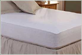 A bed with a white mattress protector on it.