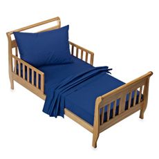 A wooden toddler bed with blue sheets and pillows.