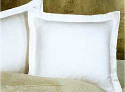 Two white pillows are sitting on top of a bed.