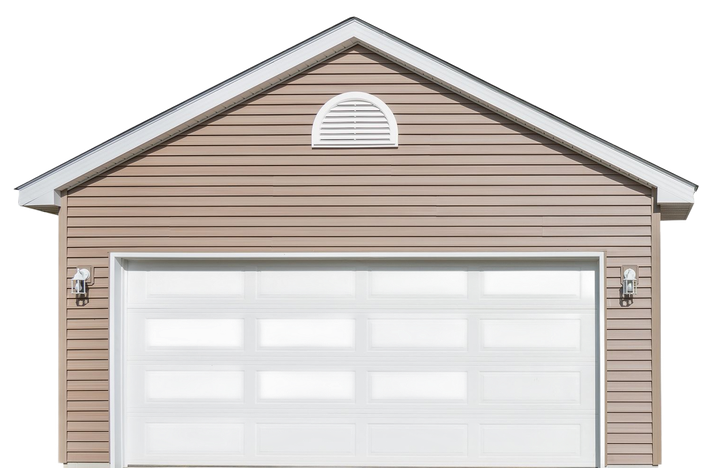 Tan detached garage with a white, multi-paneled overhead door, side wall lights, and a small arched vent under the roof.