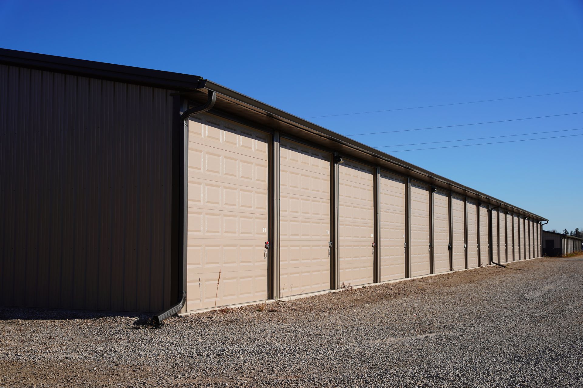 A technician in a hard hat and work coveralls installs or repairs a white sectional garage door panel.