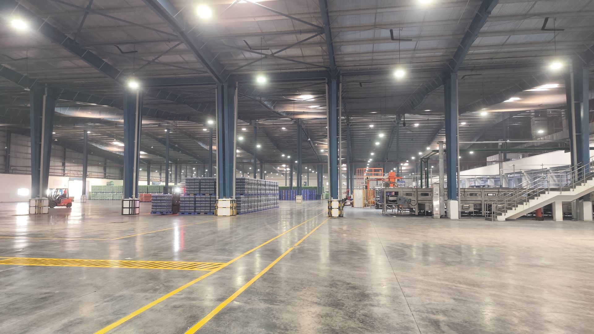 A technician in blue work coveralls inspects a wall-mounted control box next to a large, white industrial garage door.