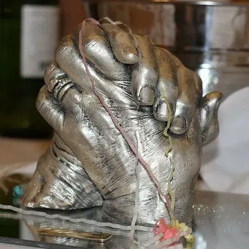 A statue of two hands holding each other on a table.