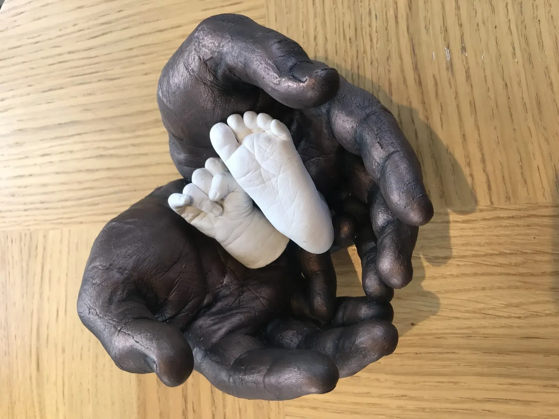 A pair of hands holding a baby 's foot on a table.