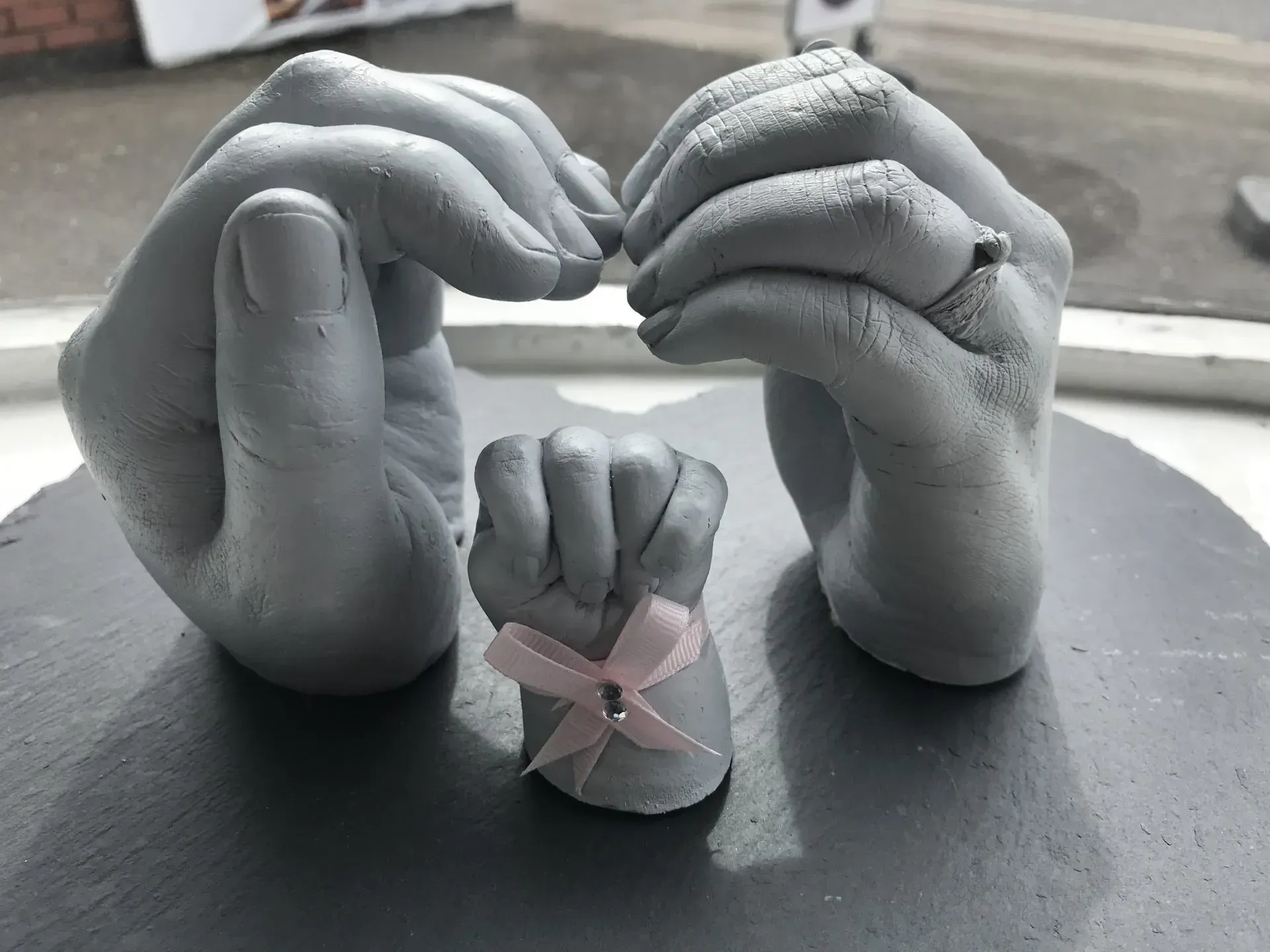 A couple of hands holding a baby 's hand on a table.