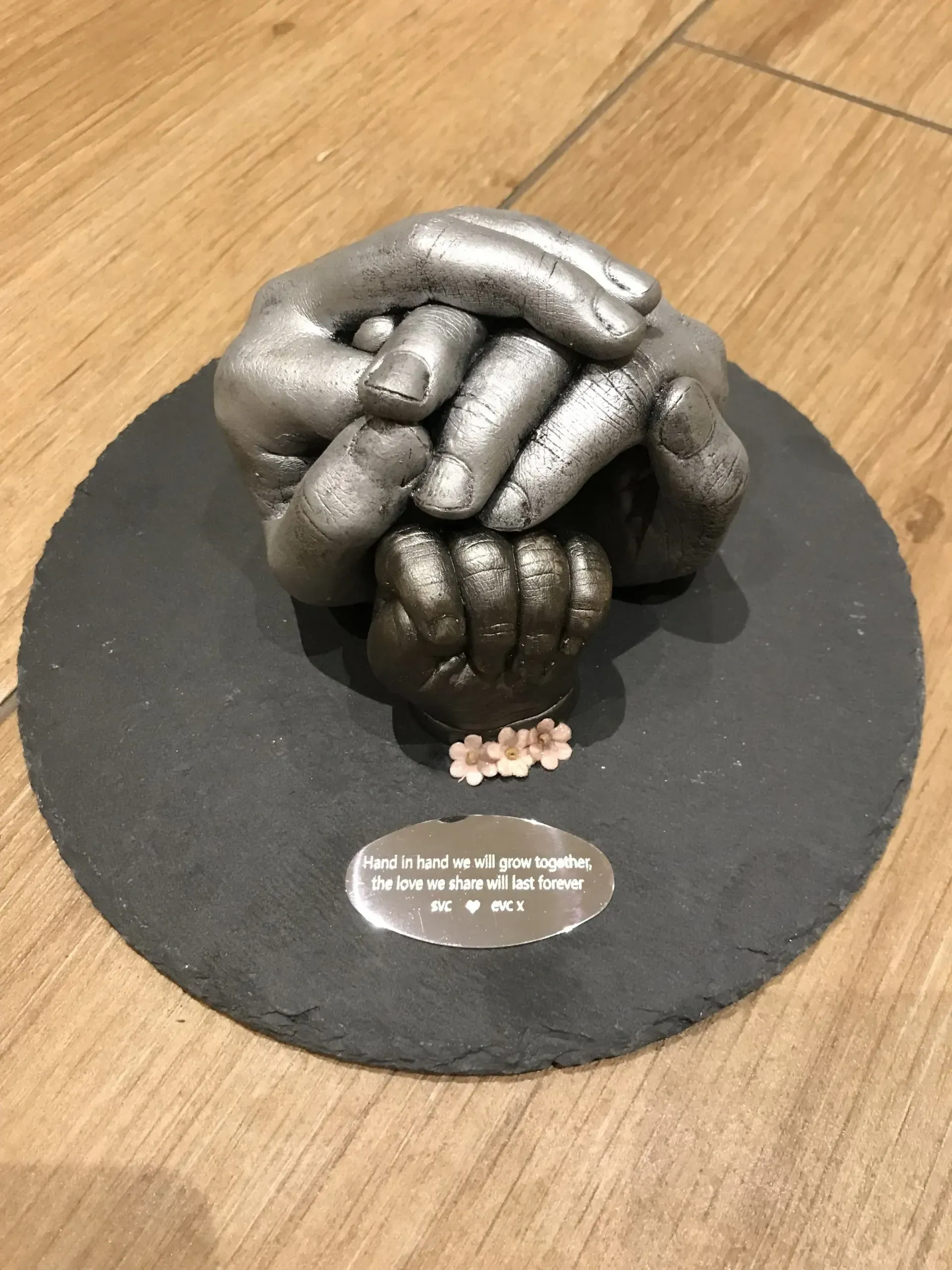 A sculpture of hands holding each other on a black plate