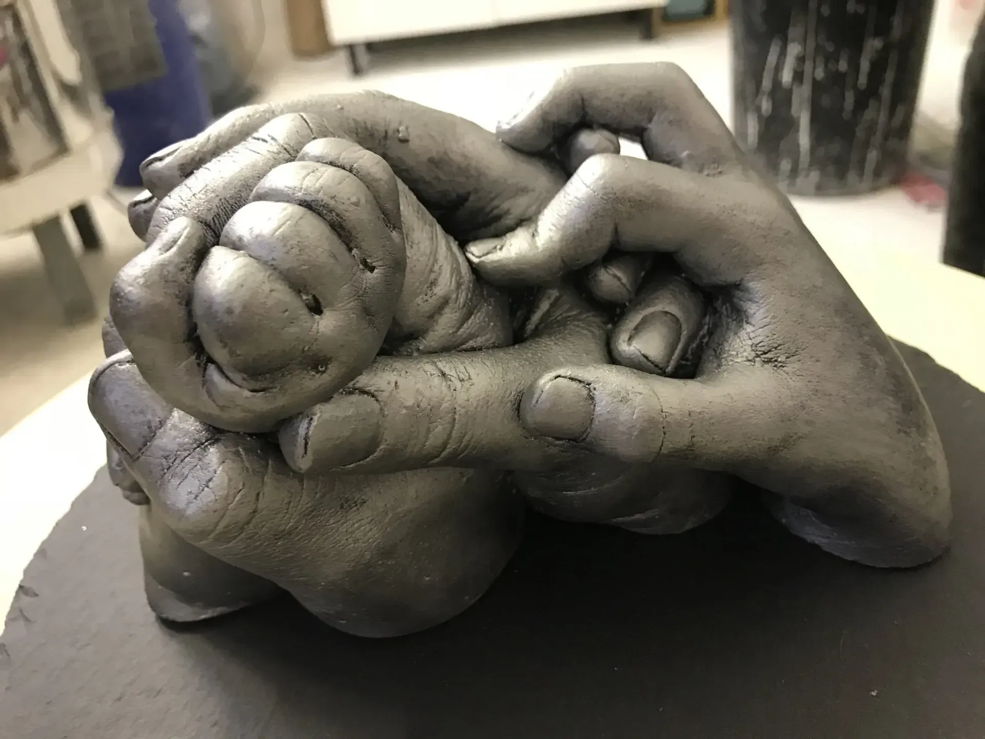 A statue of two hands holding a baby 's hand.