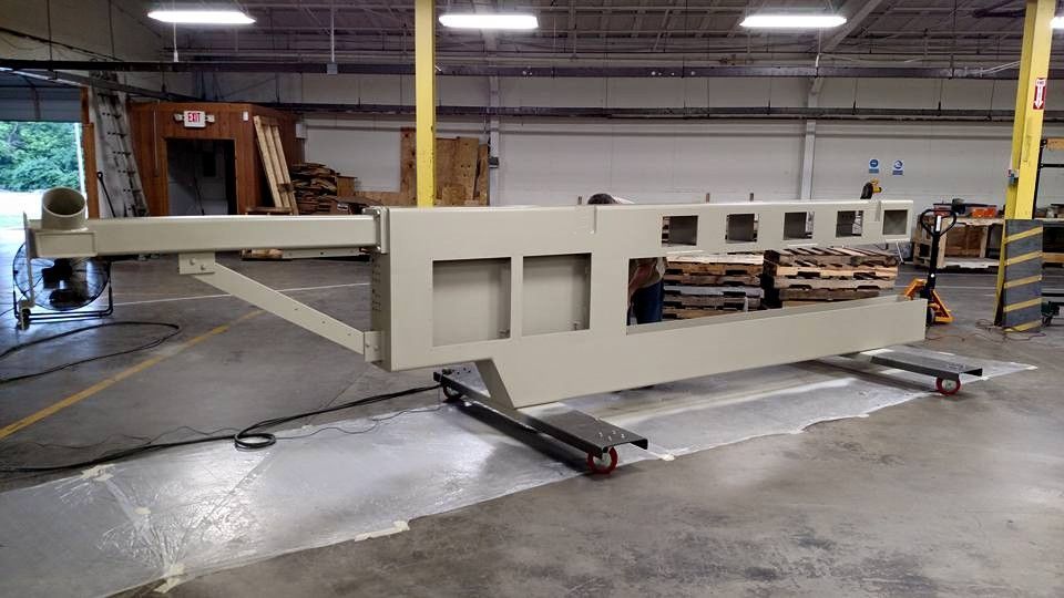 Large beige industrial structure on rolling carts inside a warehouse.