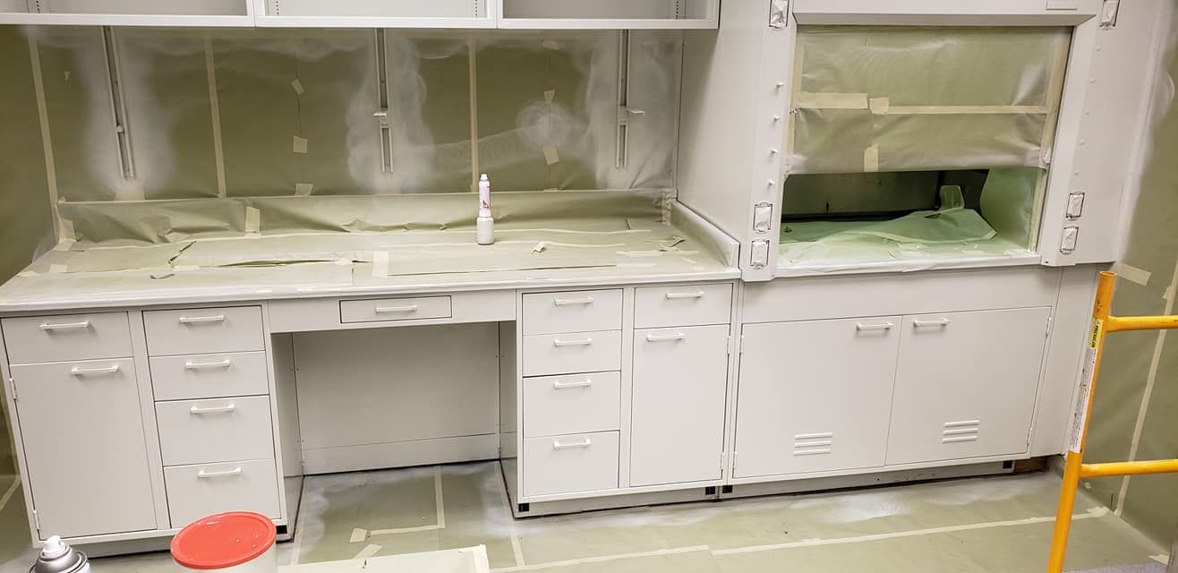 White laboratory cabinets with countertops, freshly painted, under protective coverings.