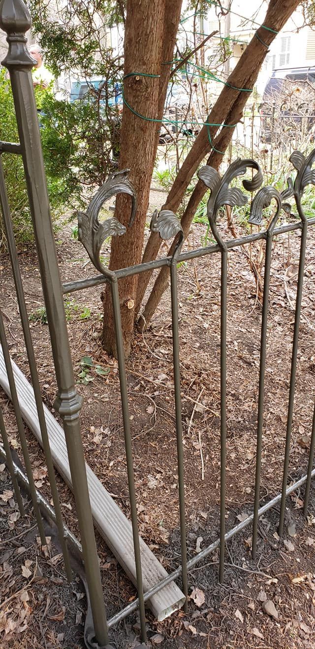 Brown wrought iron fence surrounds a tree in an outdoor setting.