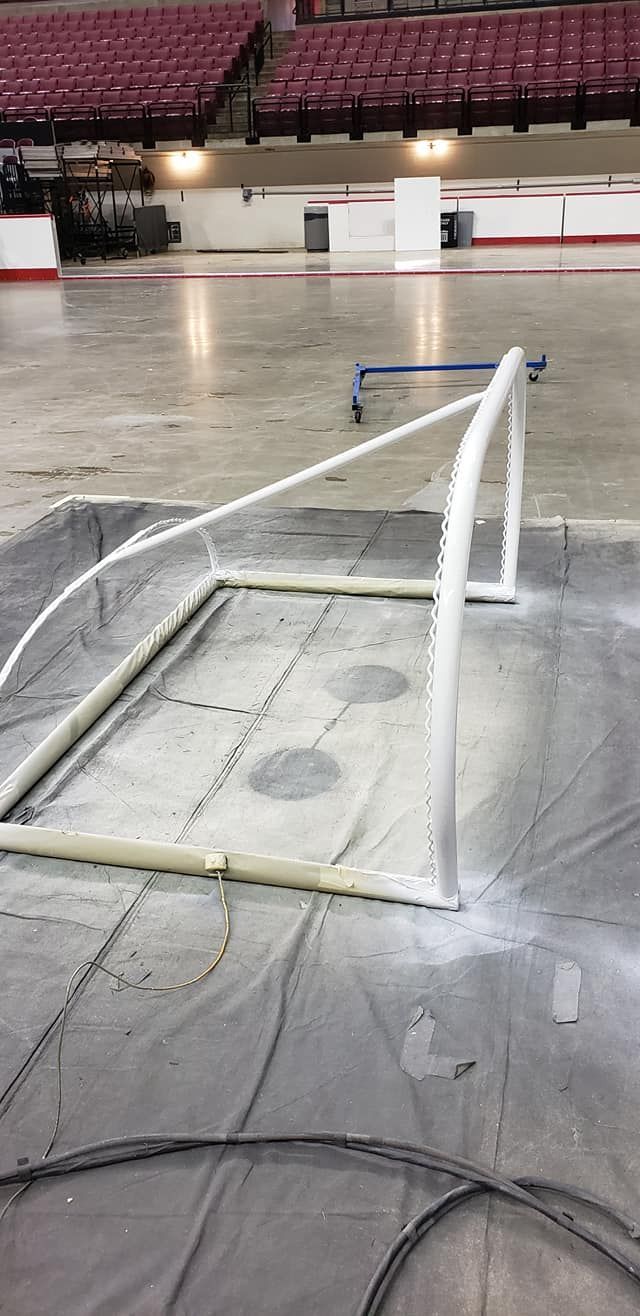 A hockey net on a tarp in an arena. Red seating and white walls are in the background.