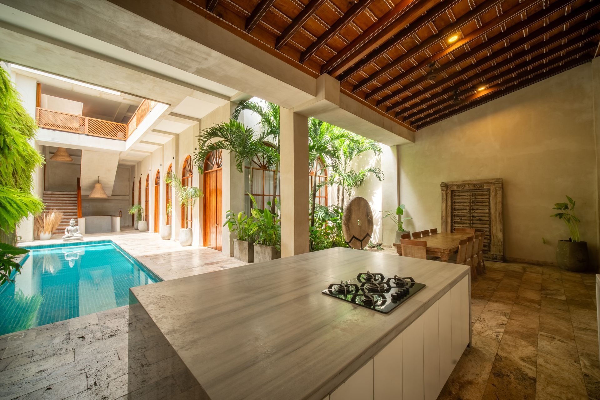 Patio de lujo con piscina, pérgola de madera y mesa de comedor de piedra en un patio al aire libre.