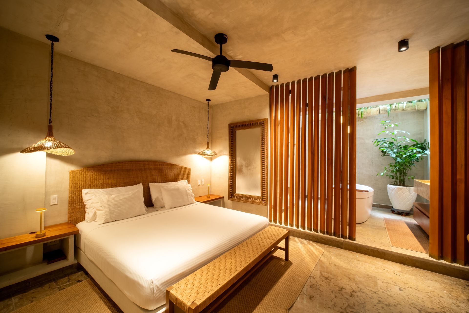 Habitación moderna con cama, iluminación cálida, detalles en madera, ventilador de techo y balcón con vista al jardín.