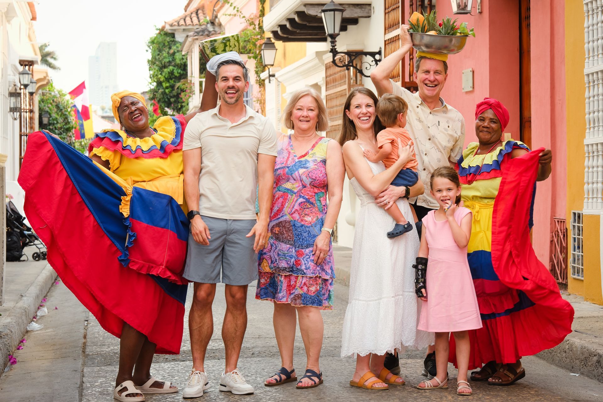 Grupo posando en una calle colorida con dos artistas sosteniendo banderas rojas y azules.