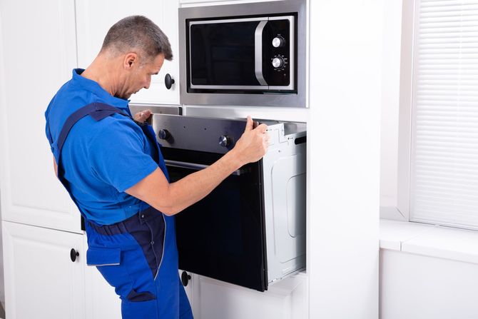 A man is installing a microwave oven in a kitchen.