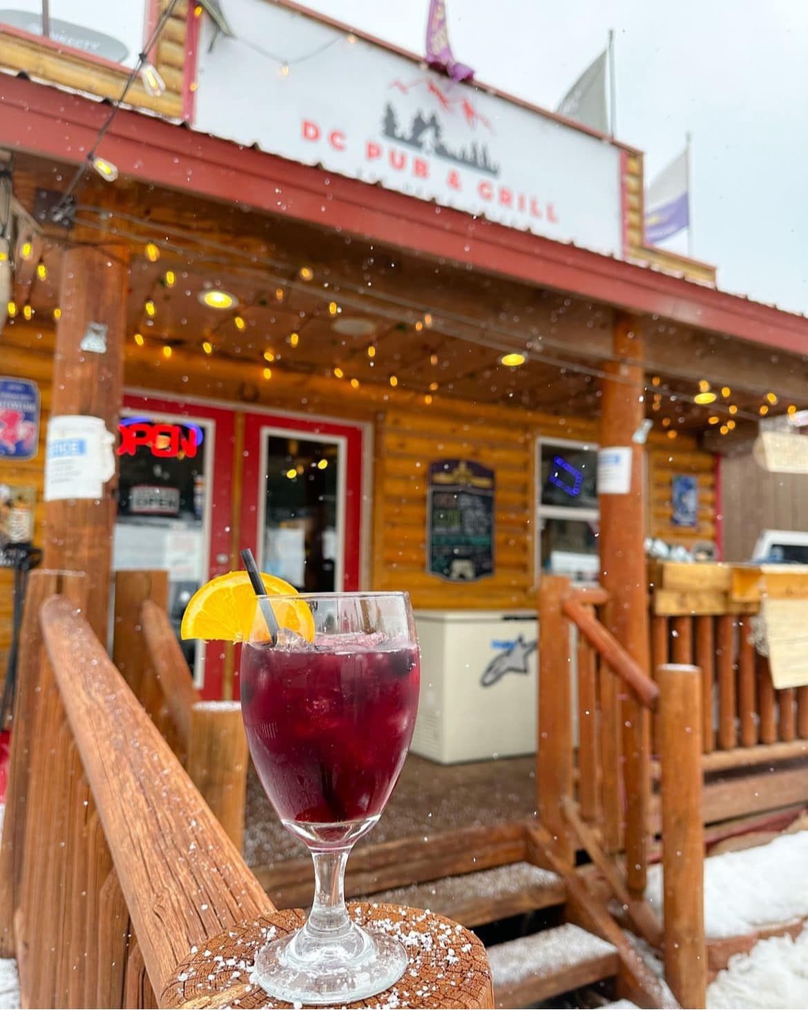 A glass of wine is on a table in front of a restaurant.