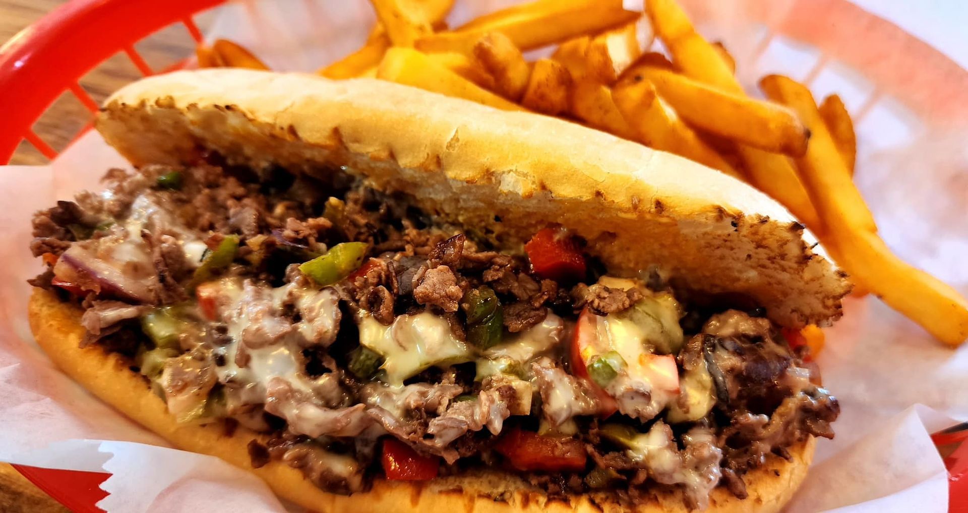 A sandwich and french fries in a basket on a table.