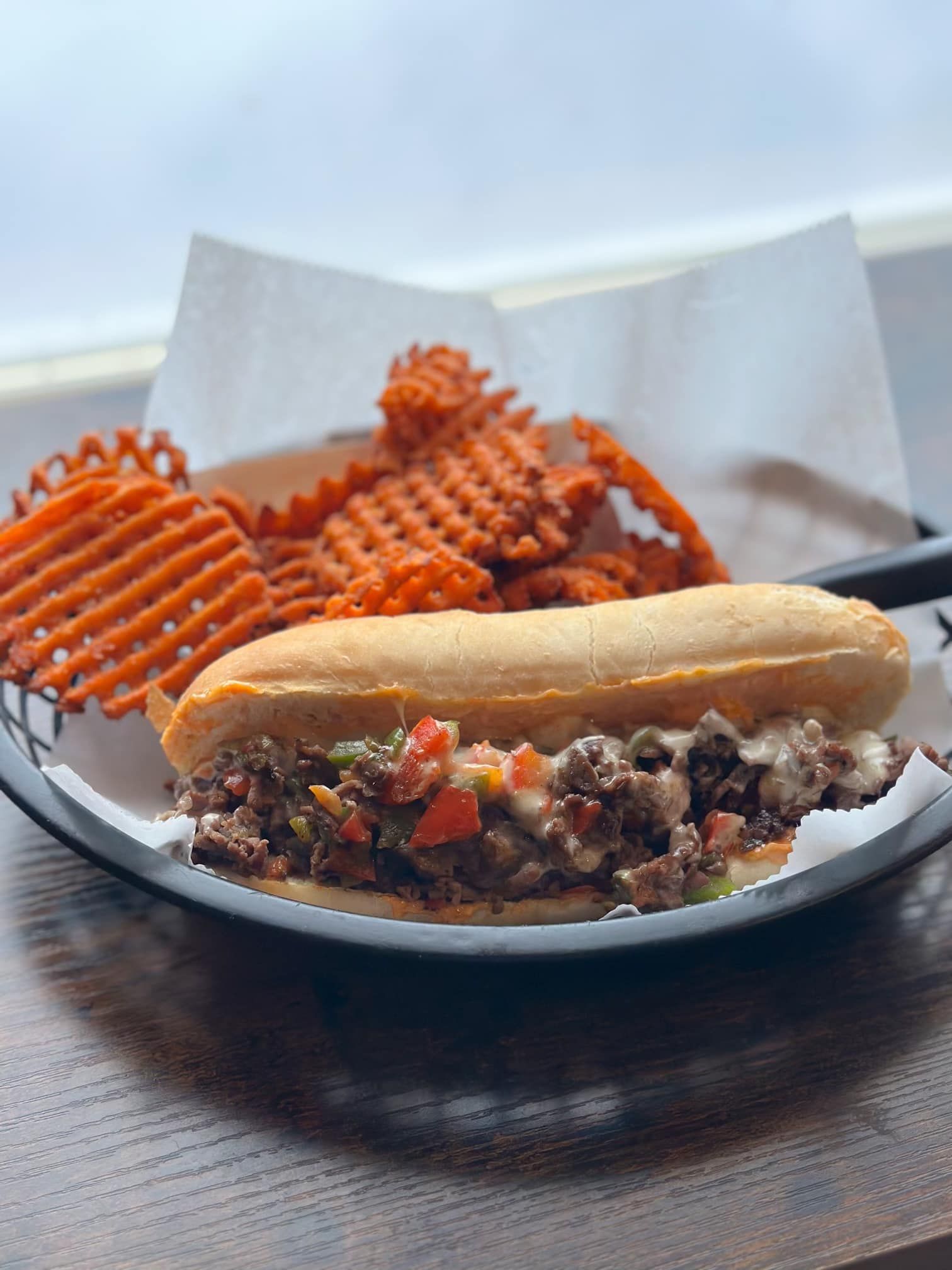A sandwich and waffle fries on a plate on a table.