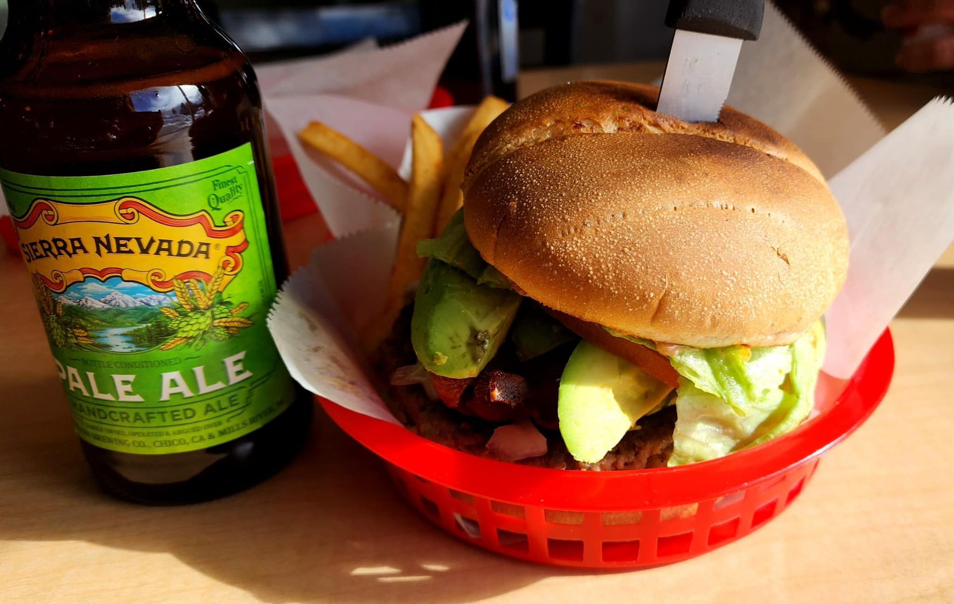 A bottle of pale ale next to a hamburger and french fries