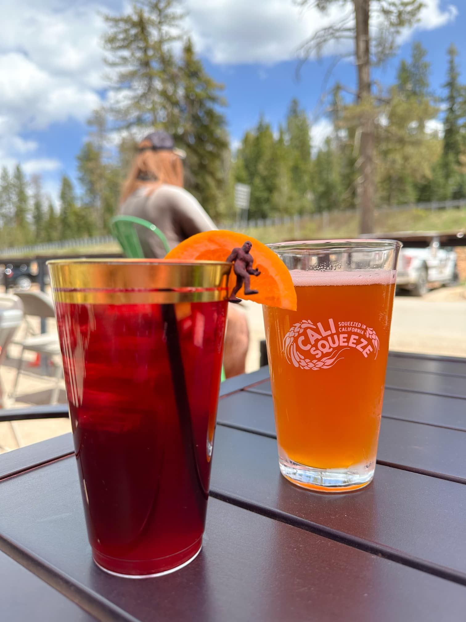 Two glasses of beer and a red drink are on a table.