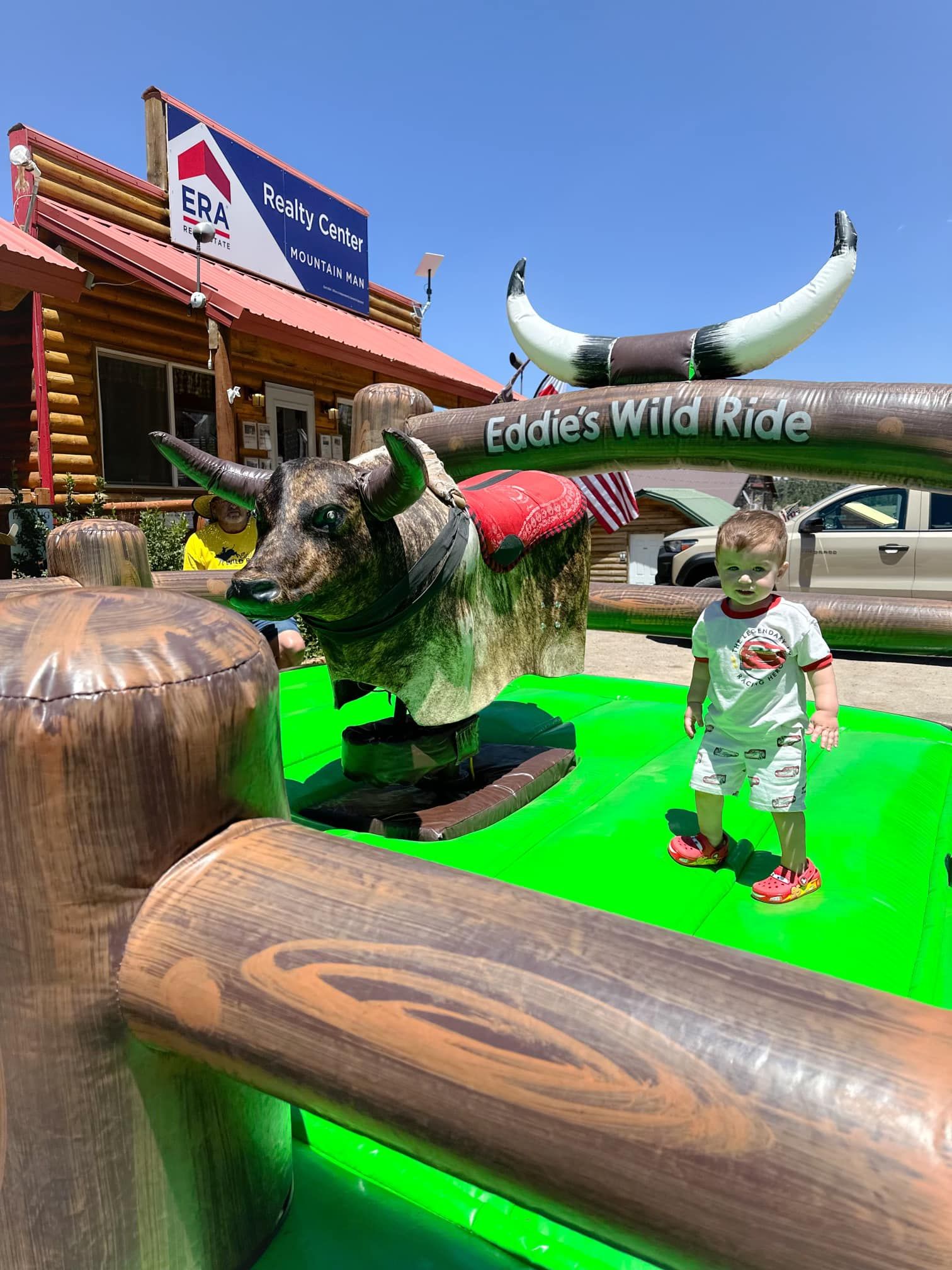 A little boy is standing next to an inflatable bull.