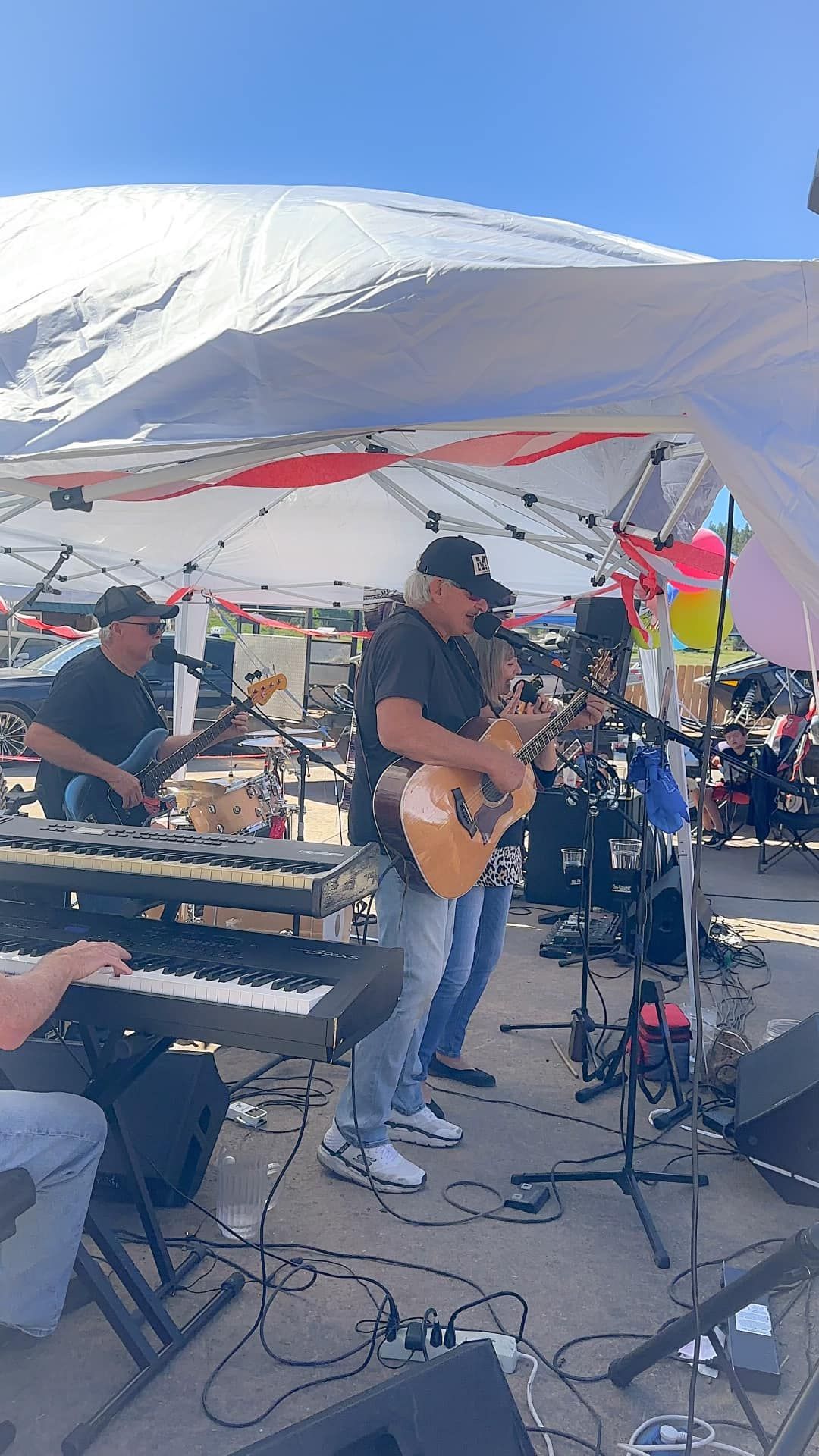 A group of people are playing instruments on a stage under a tent.