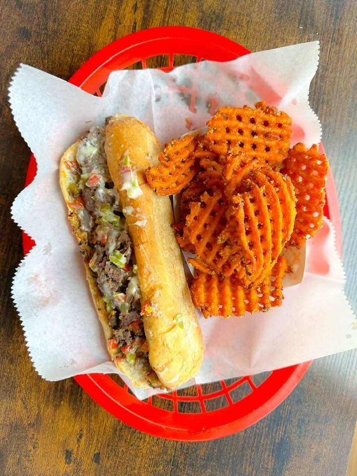 A sandwich and waffle fries in a basket on a table