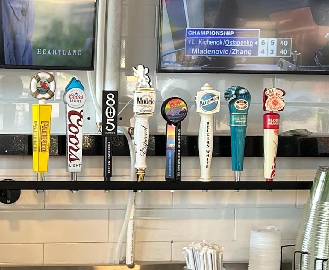 A bunch of beer taps are hanging on a wall in a restaurant.