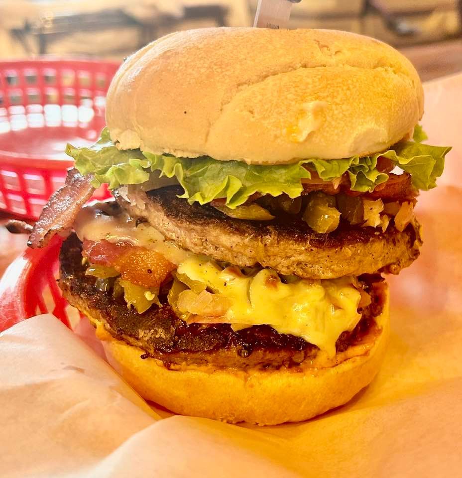 A hamburger with lettuce bacon and cheese on a bun