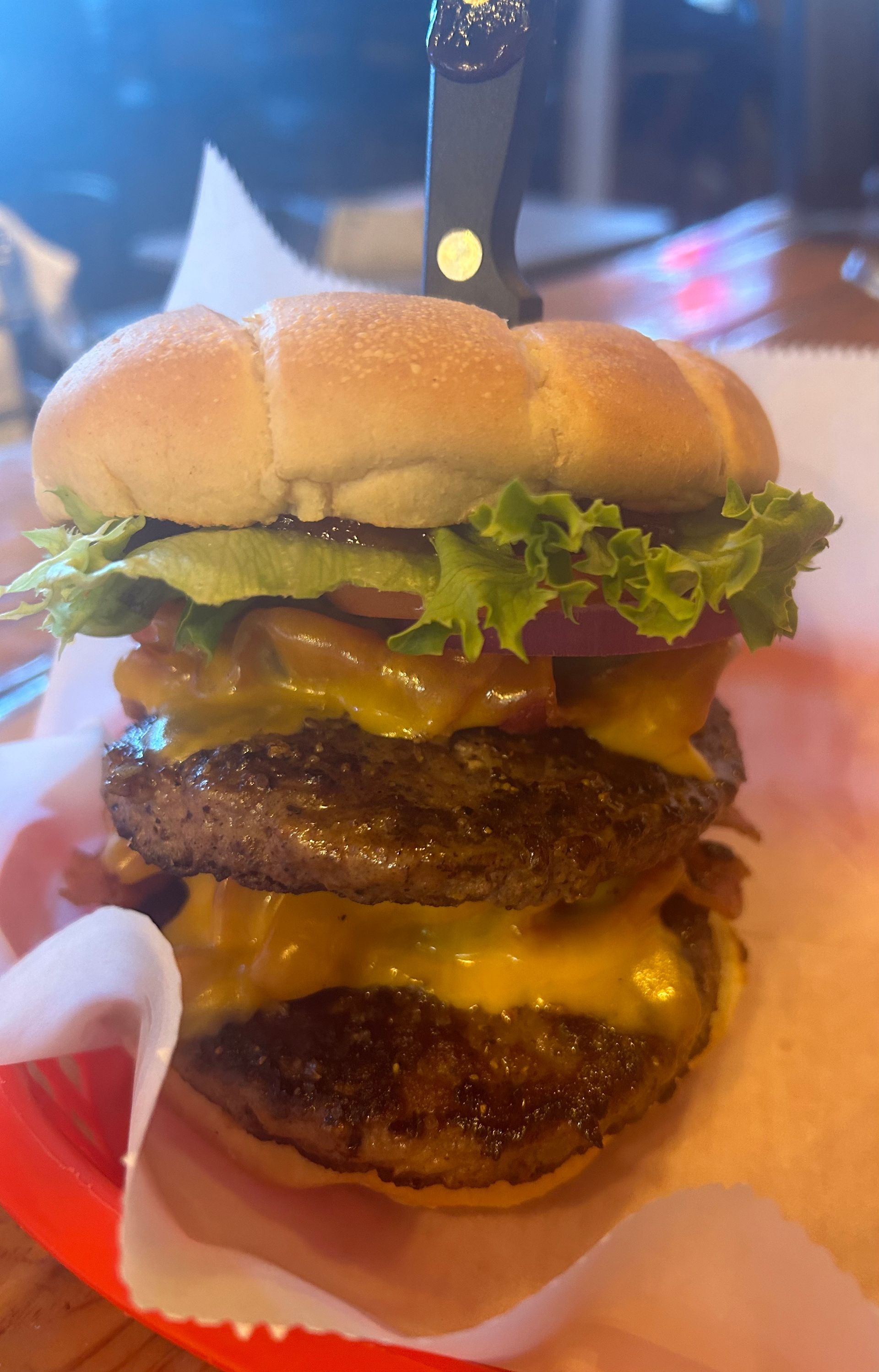 A double cheeseburger is sitting on top of a red tray on a table.