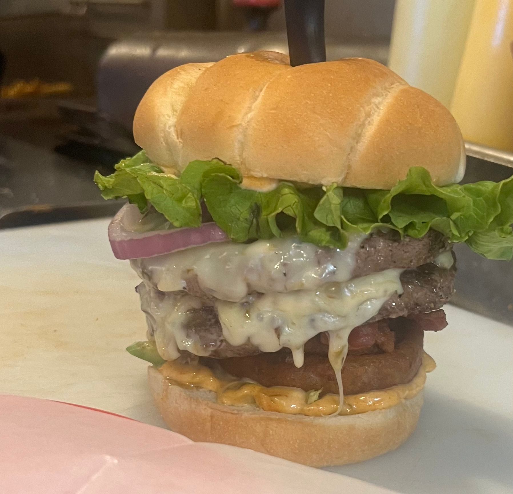 A hamburger with lettuce cheese and onions on a bun