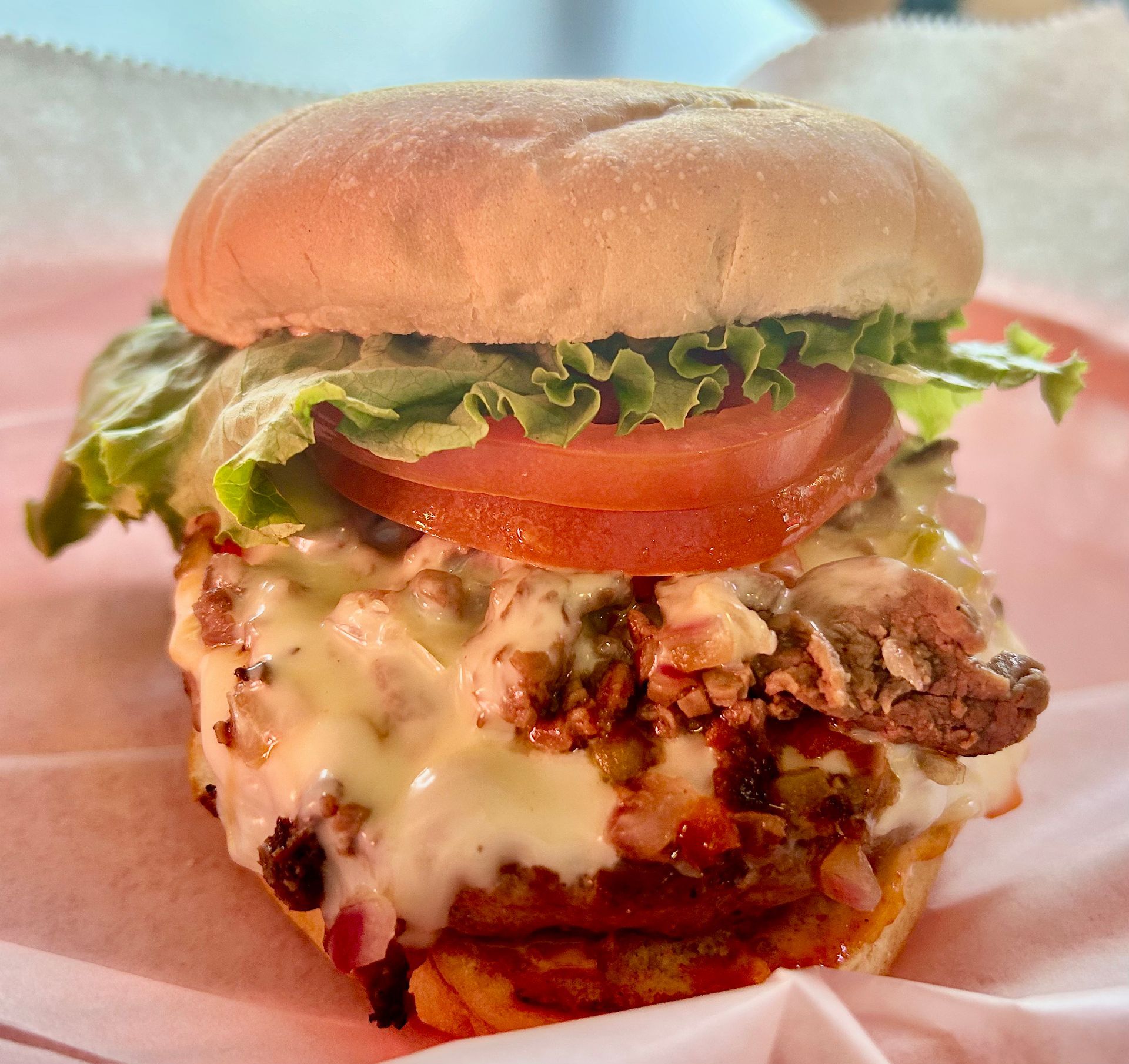 A hamburger with lettuce , tomato and cheese on a bun