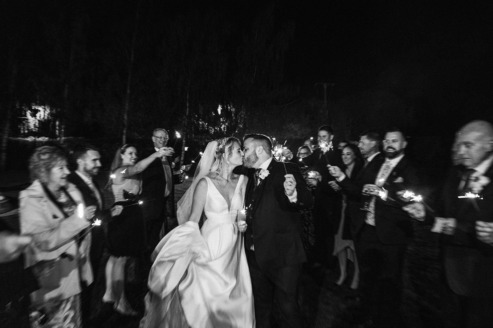 A bride and groom are standing next to each other in front of a brick wall.