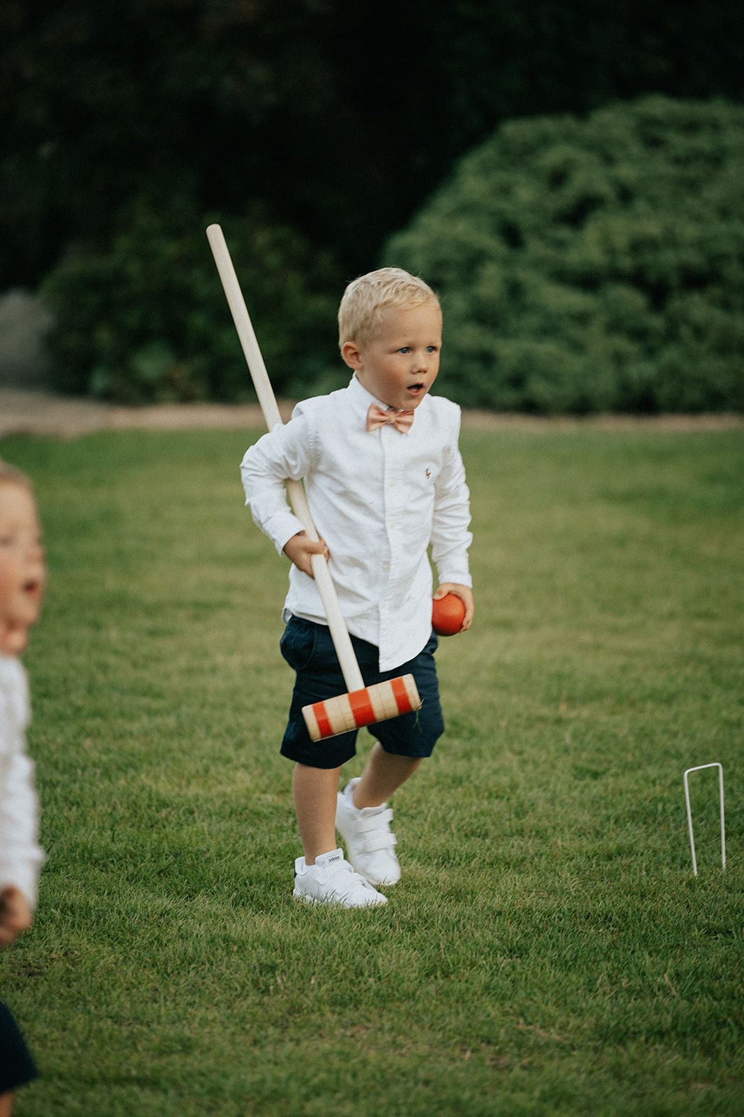 A young boy is playing a game of croquet in the grass.