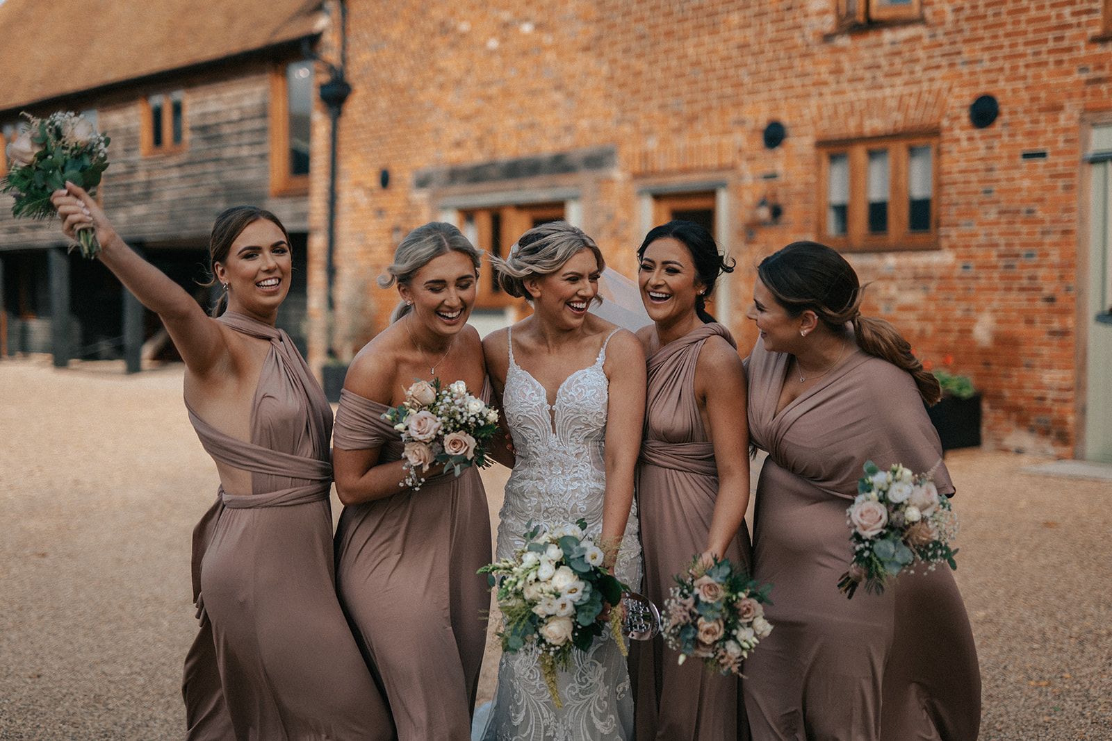 A bride and her bridesmaids are posing for a picture in front of a brick building.