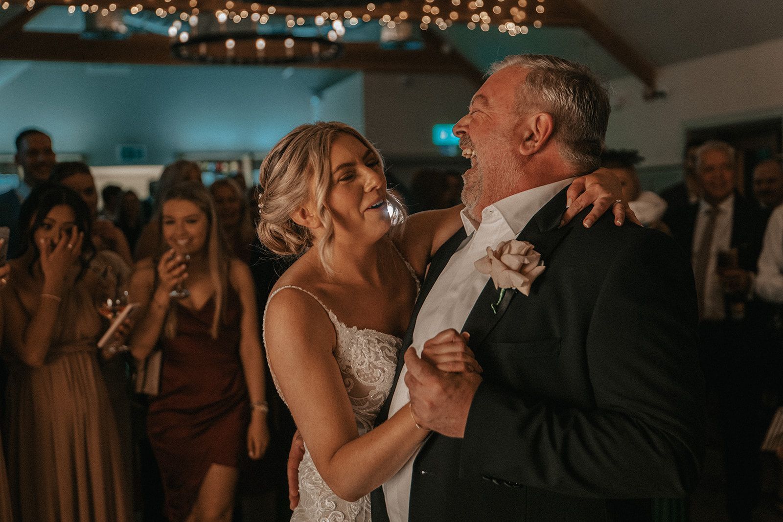 A bride and her father are dancing together at a wedding reception.
