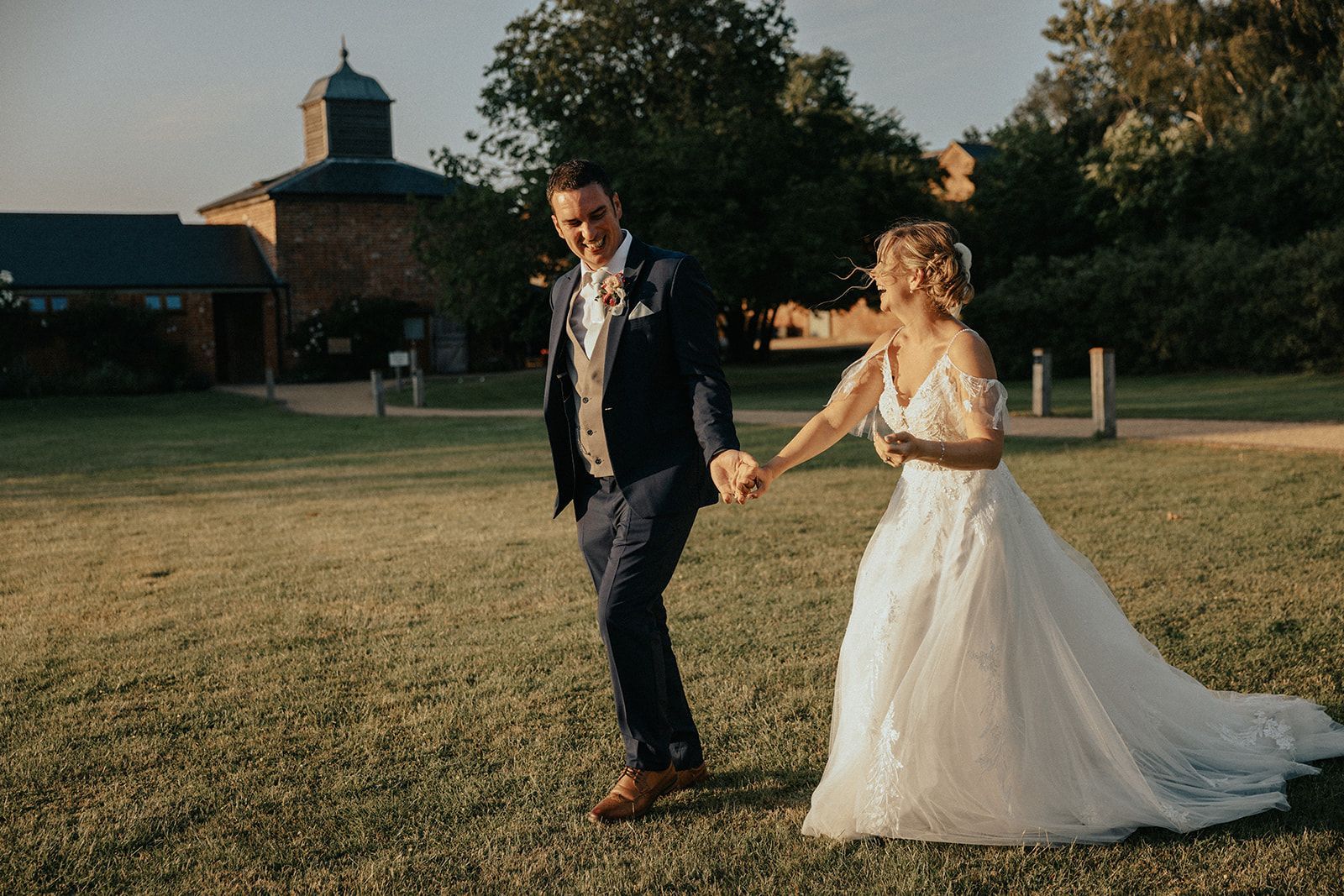 A bride and groom are holding hands and looking at each other.