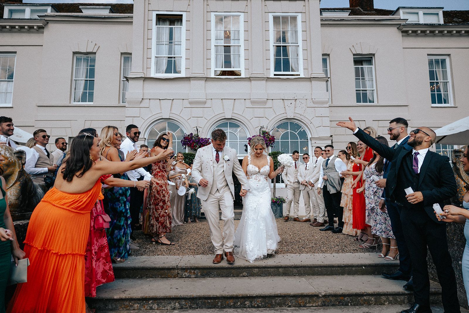 A black and white photo of a bride and groom standing in front of a brick building.
