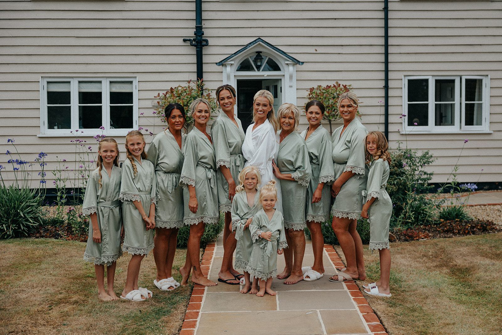 A bride and her bridesmaids are posing for a picture in front of a house.