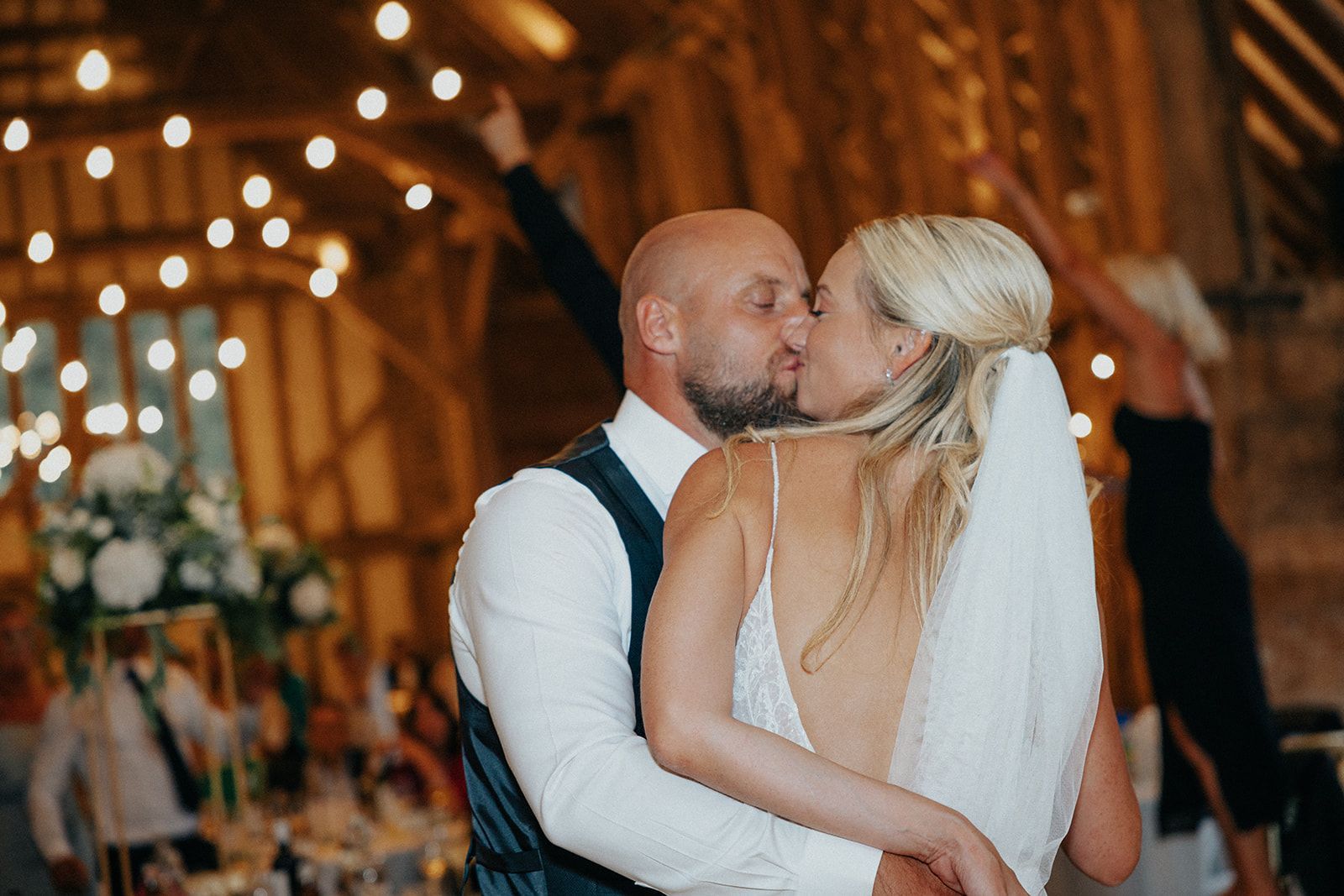 A bride and groom are kissing at their wedding reception.