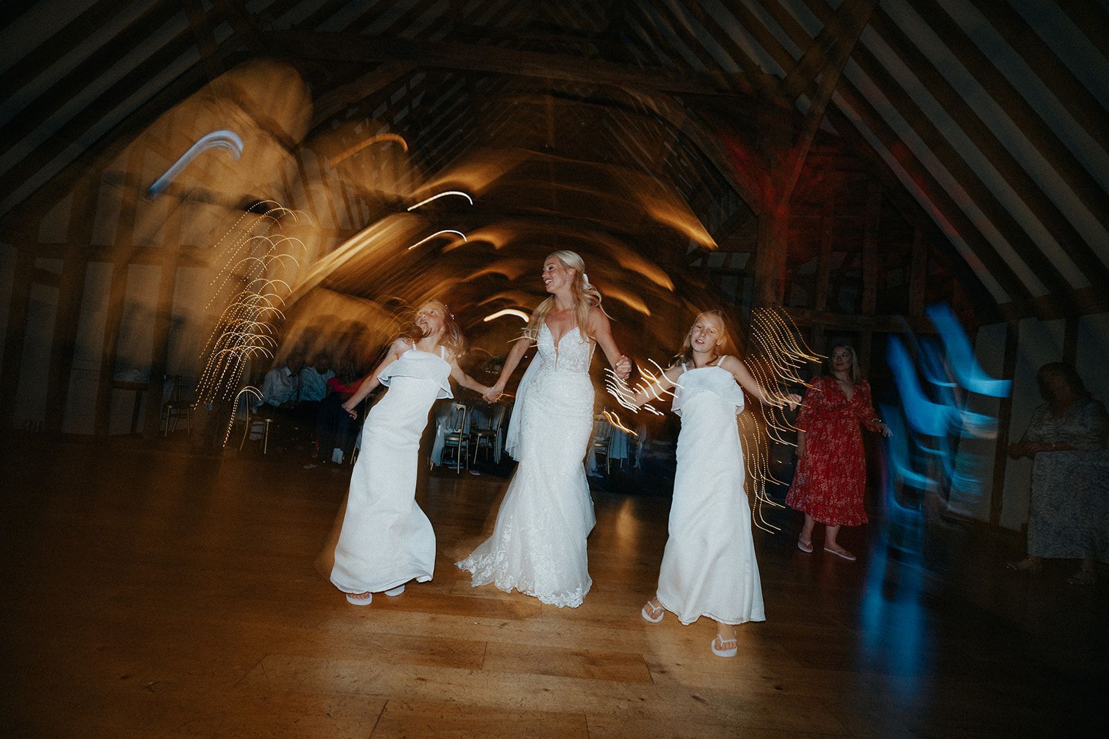 Three women in white dresses are dancing in a dark room.