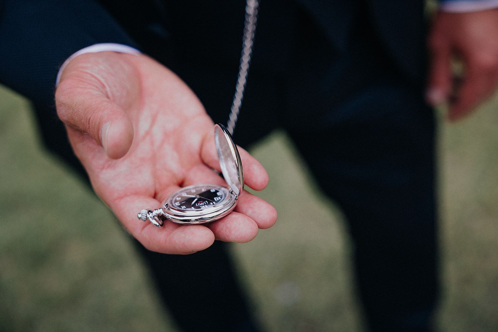 A man in a suit is holding a pocket watch in his hand.