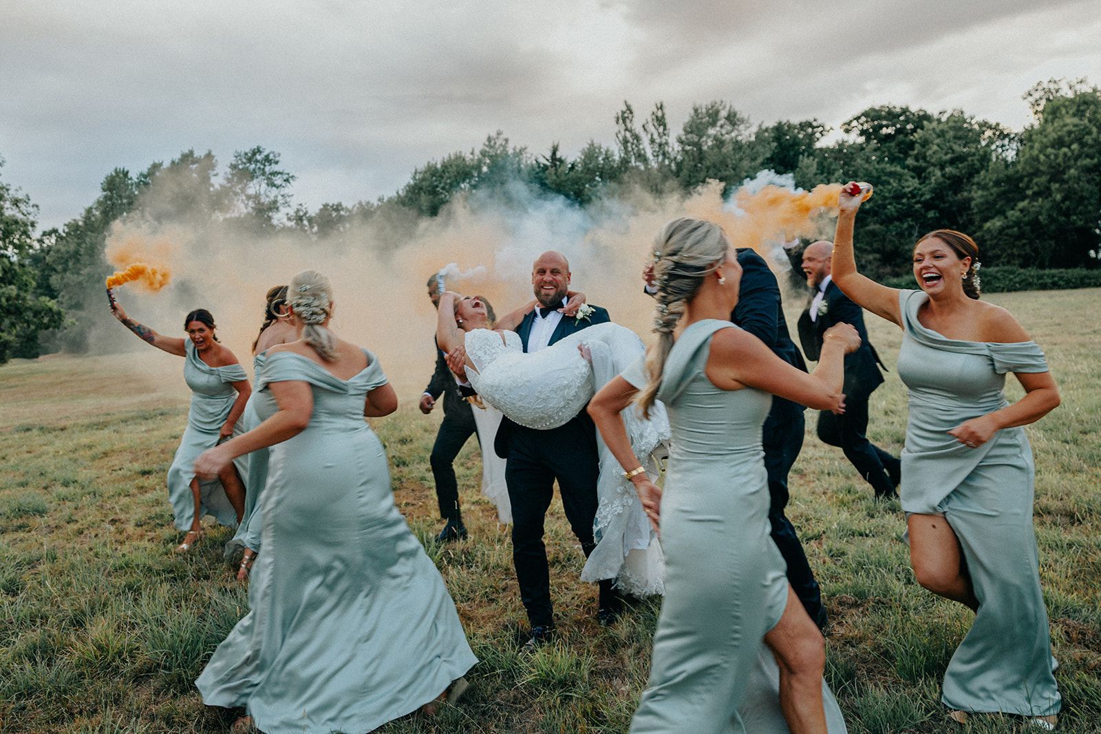 A bride and groom are dancing with their bridesmaids in a field.