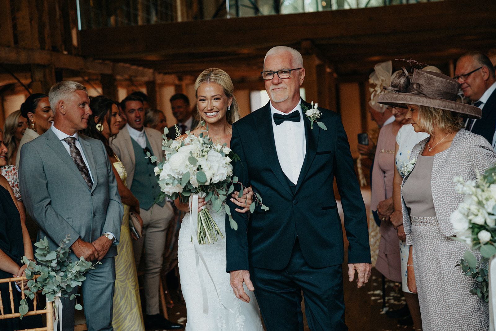 A bride and her father are walking down the aisle at a wedding.