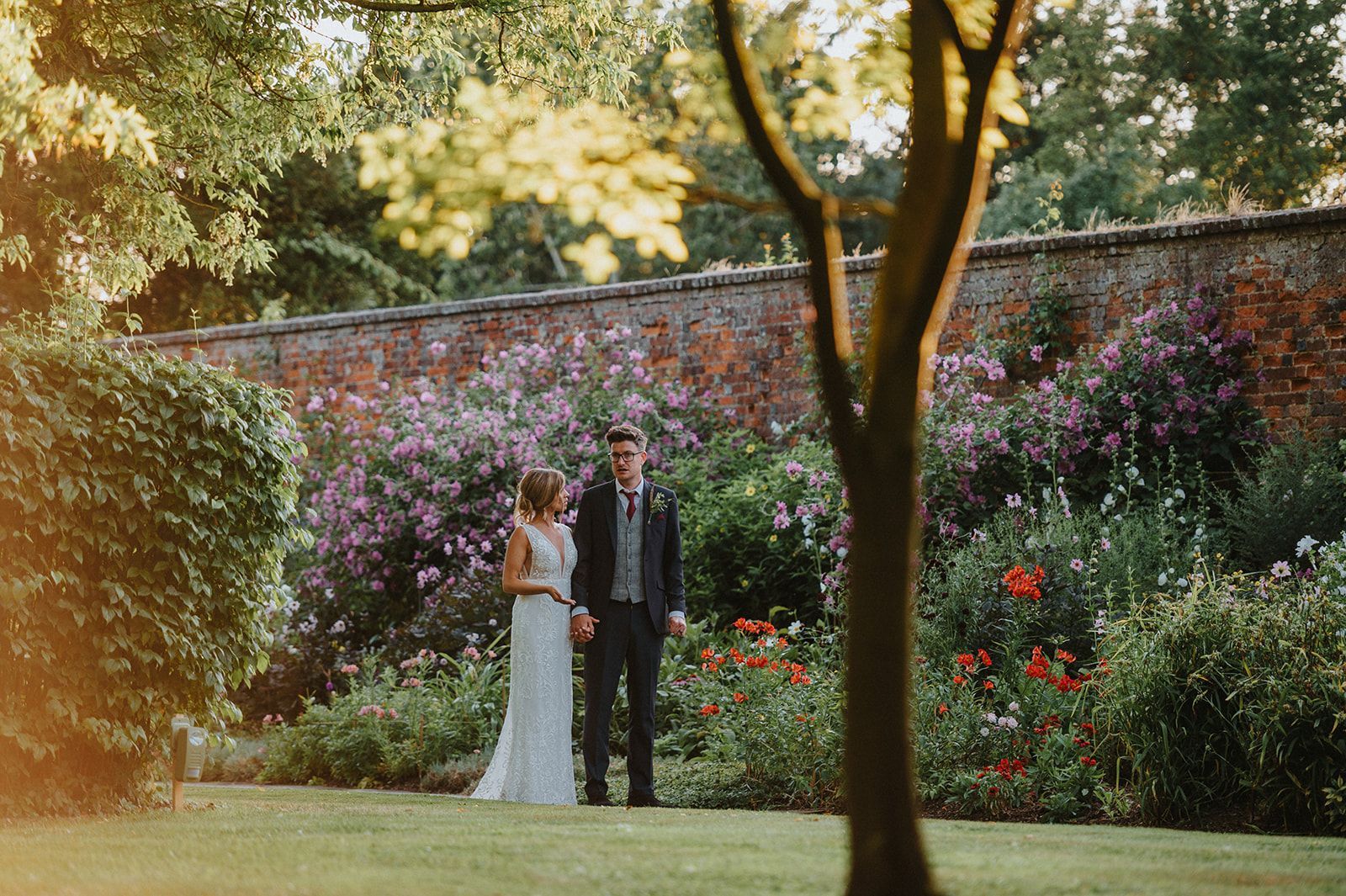 A bride and groom are standing next to each other in a garden.