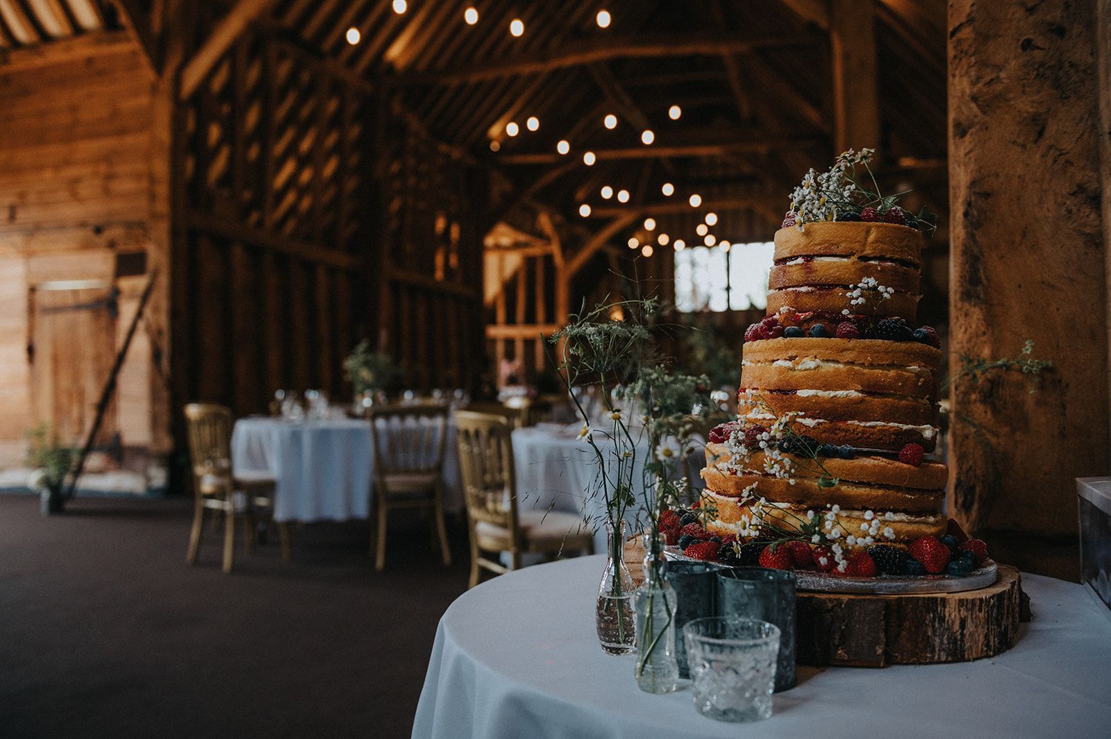 A wedding cake is sitting on a table in a barn.