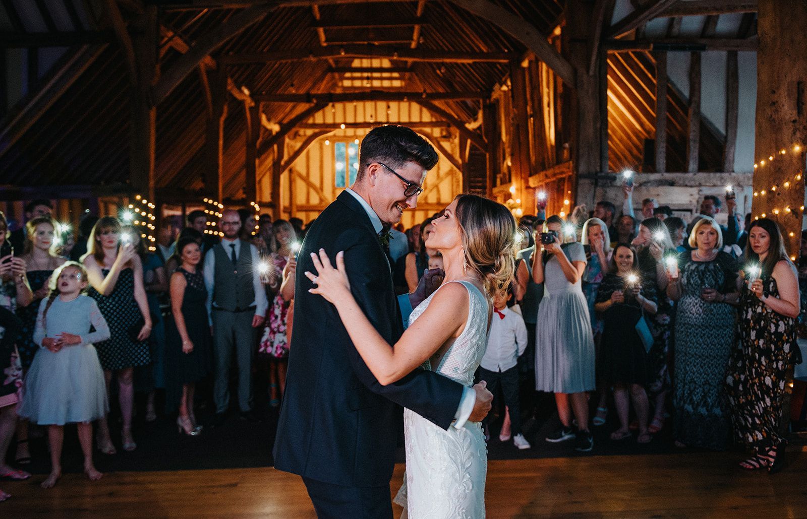 A bride and groom are dancing in front of a crowd of people at their wedding reception.